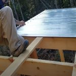 Worker installing a corrugated metal roof