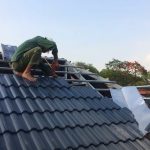 Worker installing ceramic roof tiles on the roof